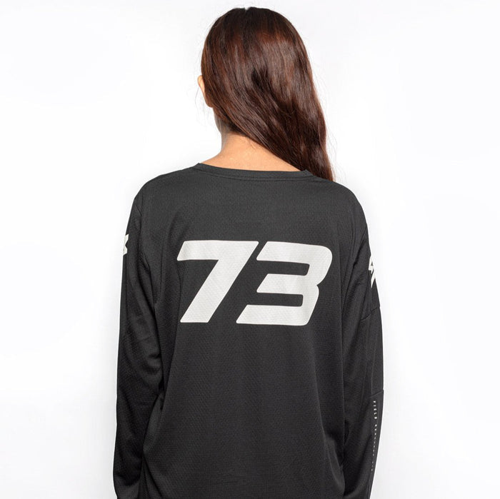 Female model back view of black Premium long sleeve athletic moto hoon jersey. @color_black