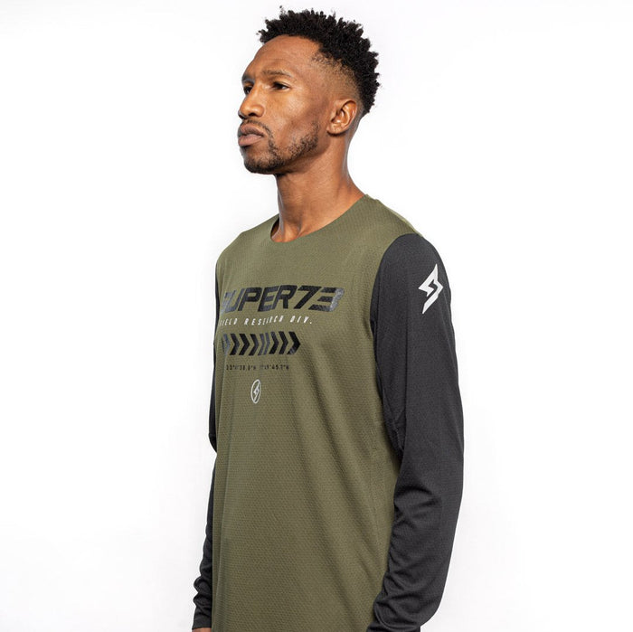 Male model side view of black and olive Premium long sleeve athletic moto hoon jersey. @color_dark fatigue