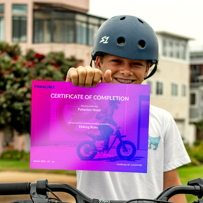 A young boy in a helmet holds up a certificate of completion for the PedalAce Ebike Safety Course