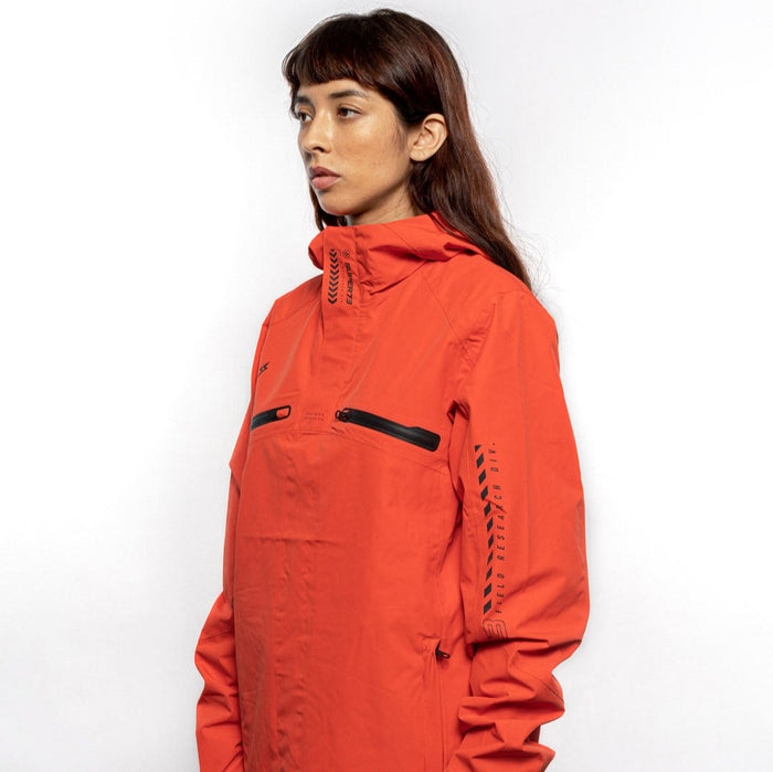 Side view of Female model wearing Vale Packable Anorak in blood orange colorway. @color_blood orange